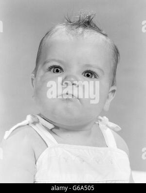 1950s 1960s PORTRAIT BABY ANGRY MAD MEAN BELLIGERENT FACIAL EXPRESSION LOOKING AT CAMERA Stock Photo