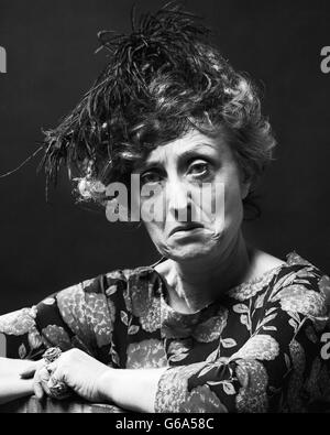 1970s PORTRAIT SENIOR WOMAN WITH MEAN SOUR SAD ANGRY FACIAL EXPRESSION WEARING A FEATHERED HAT LOOKING AT CAMERA Stock Photo