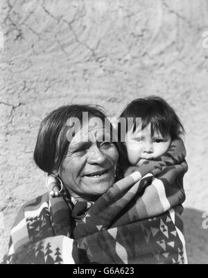 1930s SMILING NATIVE AMERICAN MAN GRANDFATHER WITH HIS GRANDSON CHILD SAN ILDEFONSO PUEBLO NEW MEXICO USA Stock Photo