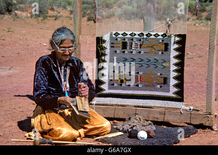 1970s SENIOR NAVAJO WOMAN WEAVING RUG CARDING WOOL Stock Photo