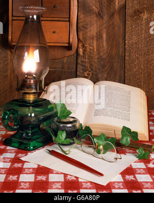 HURRICANE LAMP INKWELL PEN AND OPEN BOOK  AND PAIR OF EYEGLASSES WRITING PAPER Stock Photo