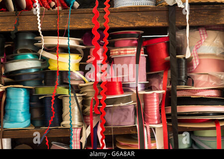 Reels of satin ribbon of various colors on wooden shelves Stock Photo