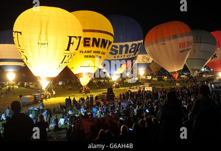 Balloons light up as they are tethered to the ground during the night glow at Ashton Court in Bristol, as part of the Bristol International Balloon Fiesta. Stock Photo