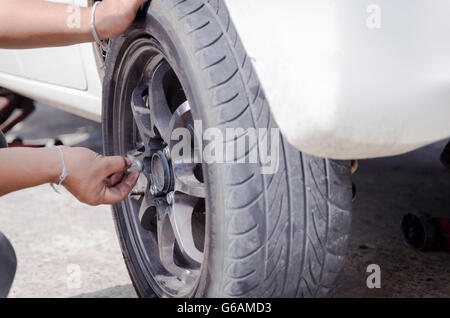 Hands of mechanic pick up the nut of car wheel and tighten Stock Photo