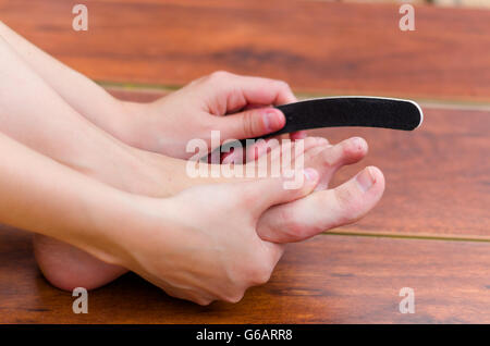 Hands making some file on feet nails, pedicure steps Stock Photo