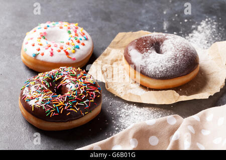 Colorful donuts on stone table Stock Photo