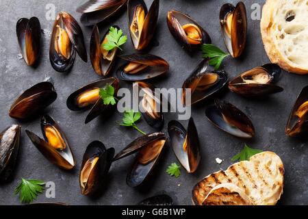 Mussels and bread toasts on stone table. Top view Stock Photo
