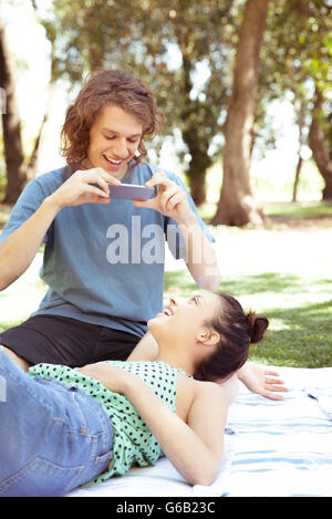 Young man photographing girlfriend with smartphone Stock Photo