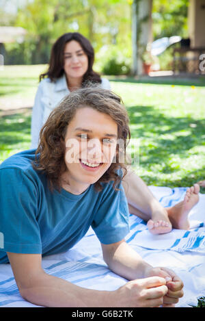 Man relaxing on picnic blanket with friend Stock Photo