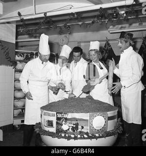 Stars of the London Palladium pantomime Puss in Boots help chef Albert Beeches (second left) stir a giant Australian Christmas pudding at Cadby Hall in London. From left: Mike Winters, Albert Beeches, Frankie Vaughan, Joan Regan and Bernie Winters. 107 towns and cities in Britain will receive a Christmas pudding as a gift from Australia's dried fruit growers. Stock Photo