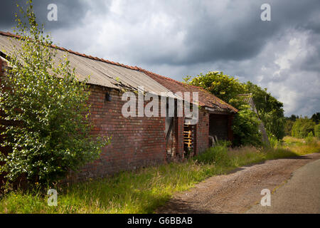 A red brick farmhouse barn in Southport, Merseyside, UK. 24th June, 2016. UK Weather: Dark Stormy Clouds over Lancashire. A day of little sunshine and heavy showers, some of which will turn thundery as daytime temperatures begin to rise. Stock Photo
