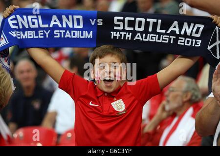 A young England fan holds up a scarf in support of his team in the stands. Stock Photo