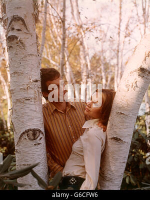 1970s ROMANTIC COUPLE LEANING ON BIRCH TREE  TRUNK AUTUMN Stock Photo