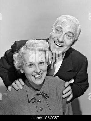 1950s SMILING PORTRAIT MIDDLE-AGED COUPLE MAN STANDING ABOVE WOMAN WITH HANDS ON HER SHOULDERS Stock Photo