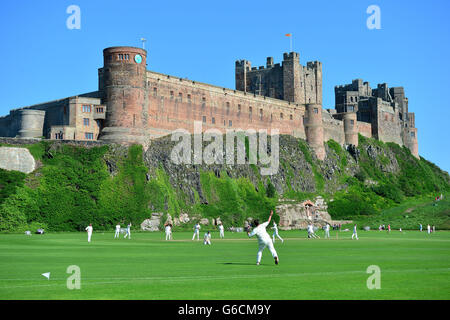 A cricket match between Bamburgh and Ovingham beneath Bamburgh Castle, Northumberland. Stock Photo