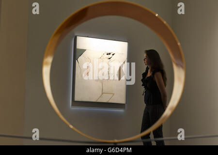 A Sotheby's employee seen through a sculpture called 'Untitled (Circle)' by David Annesley looks a '42nd Street' by Rita Donagh, part of The New Situation - Art in London in the Sixties exhibition at Sotheby's auction house in London. The exhibition runs at the auction house from 4 - 11 September when a selection of works will then go on sale. Stock Photo