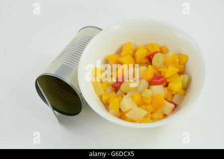 Canned fruit cocktail in bowl with can on white background Stock Photo
