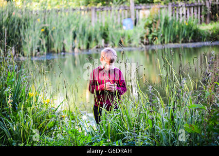 child using his mobile phone next to the lake Stock Photo