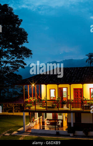 A home glows warmly at dusk on a coffee farm in rural Colombia. Stock Photo