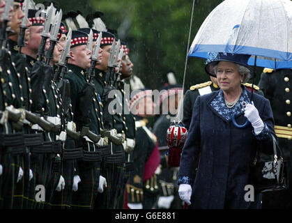 Queen Elizabeth II carrying an umbrella to protect her from the torrential rain, inspects members of the 1st Battalion The Royal Scots (Royal Regiment), at the traditional Ceremony of the Keys outside the Palace of Holyroodhouse in Edinburgh. Stock Photo
