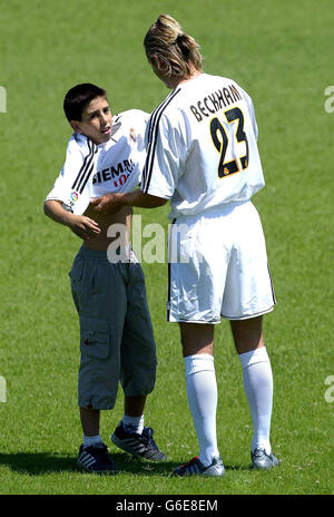 Real Madrid's new signing David Beckham helps a young fan, Alfonso aged 11, who ran on to the pitch into a Real Madrid shirt at the club's training ground, the Pebellon Raimundo Saporta Stadium in Madrid. Stock Photo