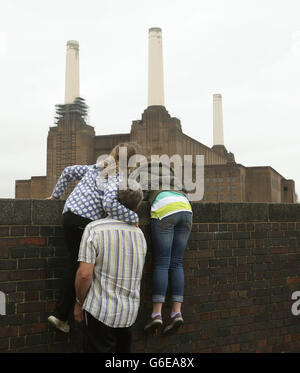 People peer over a wall for a view of Battersea Power Station during the Open House London architectural showcase, in London, as entry for visitors was closed early due to oversubscription. Stock Photo