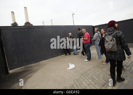 People queuing to look through a hole in a gate for a view of Battersea Power Station, during the Open House London architectural showcase, in London, as entry for visitors was closed early due to oversubscription. Stock Photo