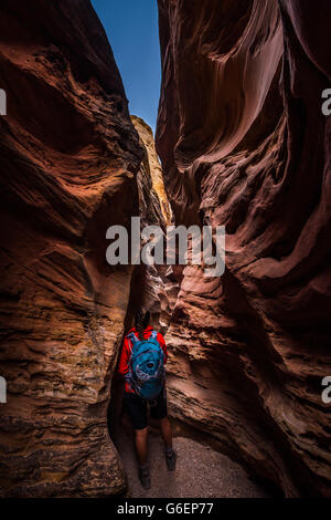 Young Woman Backpacker exploring narrow slot canyon Little Wild Horse Goblin Valley Stock Photo