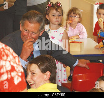 The Prince of Wales laughs after Jac Williams, 2, knocks two mirrors from the wall during his visit to the Penyreglyn community project at Treherbert, Rhondda. Stock Photo