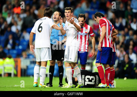 Real Madrid's Gareth Bale (centre) argues his point after fouling the Atletico Madrid goalkeeper Thibaut Courtois (floor) Stock Photo