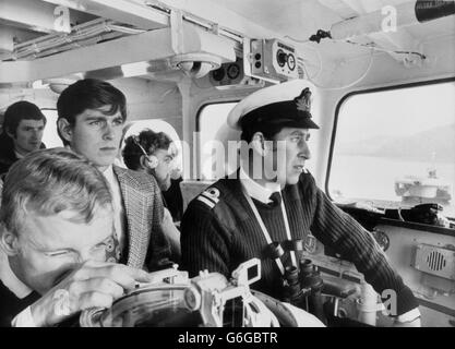 Sixteen-year-old Prince Andrew during a trip aboard his Royal brother's ship, HMS Bronington, off the coast of Scotland. He is flanked by his brother, the skipper, Lt The Prince of Wales (r), and Lt James Ringrose, the officer of the Watch on the trip. They are inside the glassed-in bridge of the 360-ton vessel. Stock Photo