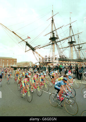 Riders pass HMS Victory at the start of the 2nd leg of Le Tour, the new British stage of the Tour de France, in Portsmouth Dockyard. Stock Photo