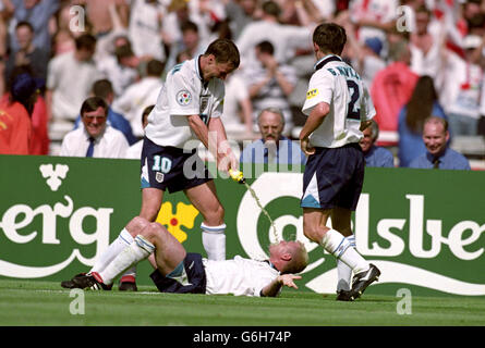 England's Paul Gascoigne (on floor) re-enacts the infamous Dentist's Chair incident with Teddy Sheringham (left) after scoring the second goal. Teammate Gary Neville (right) looks on Stock Photo