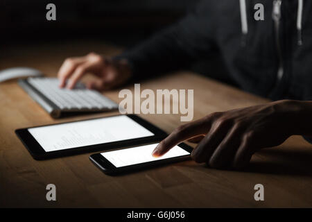 Closeup of young man using blank screen and cell phone on the table Stock Photo