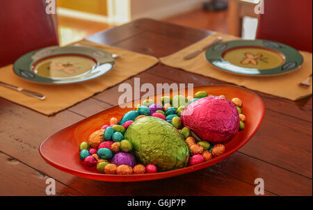 Colourful chocolate easter eggs ready for after dinner in a bowl on a table set for dinner at Easter. Stock Photo