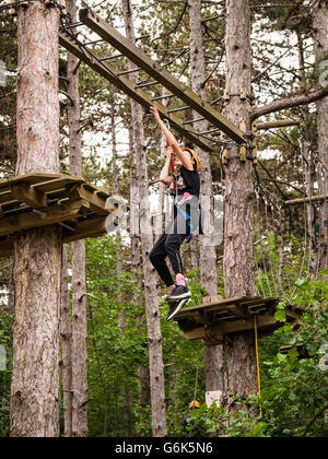 Child hanging on a safety rope in an adventure course.