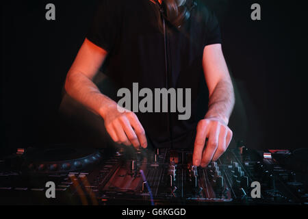 Closeup of dj standing and mixing tracks in nightclub Stock Photo