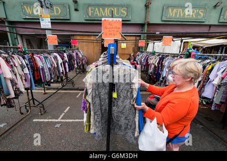 Woman browsing second hand clothes at Barras Market in Gallowgate Glasgow, United Kingdom Stock Photo