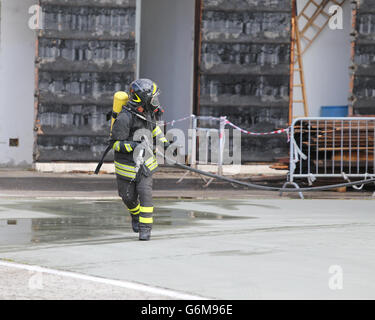 firefighters with breathing apparatus and oxygen cylinder runs with the spear fighting to tame the fire Stock Photo