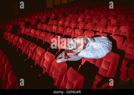 Ballerina sitting in the empty auditorium theater Stock Photo