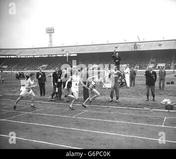 Christopher Chataway hands over the baton to GW Nankeville in the first change-over of the 4 x 1 mile relay race between Great Britain and France at the White City Stadium. The British team won with a record time. Stock Photo