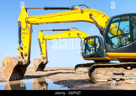 Yellow excavator on construction site against clear blue sky Stock Photo
