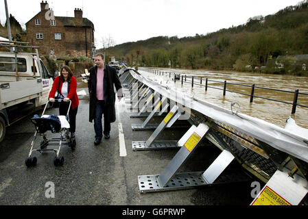 Ironbridge residents walk along the flooded Warfage Bank, protected by the temporary flood defence barriers, after water levels on the River Severn rose, Ironbridge nr Telford , Shropshire. Stock Photo