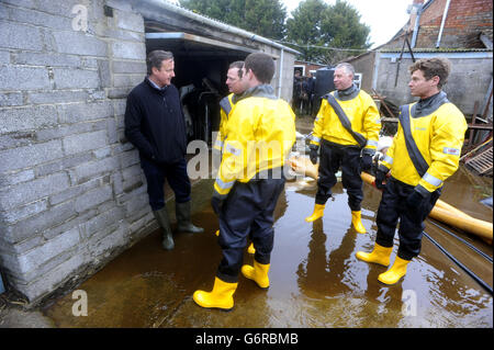 Prime Minister David Cameron talks with emergency service workers (names not known) during a visit to Goodings Farm in Fordgate, Somerset.