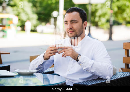 Confident successful businessman in suit enjoying a cup of coffee while having work break lunch in modern restaurant,young intelligent man or entrepreneur relaxing in outdoors cafe looking pensive Stock Photo