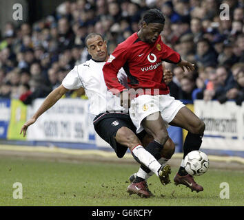 Manchester United's Louis Saha (R) shields the ball from Fulham defender Alain Goma during the Barclaycard Premiership match at Loftus Road, London, Saturday February 28, 2004. Stock Photo