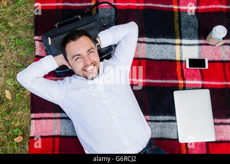 Happy young man with laptop relaxing on the grass, view from the top Stock Photo
