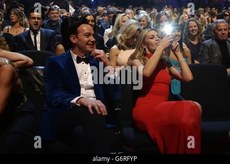Craig Revel Horwood and Abbey Clancey take photographs during the 2014 National Television Awards at the O2 Arena, London. Stock Photo