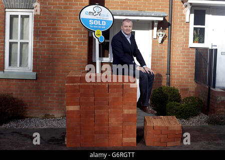 Russell Quirk, Founder of low cost online estate agency eMoov.co.uk, compares the different levels of commission earned comparatively by UK high street estate agents versus eMoov.co.uk, represented by piles of bricks outside a property in Brentwood, Essex. Stock Photo