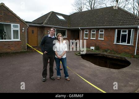 Phil and Liz Conran stand outside their home, in Main Road, Walter's Ash, High Wycombe, Buckinghamshire, after a 30ft-deep sinkhole opened up in the driveway yesterday and swallowed their car. Stock Photo